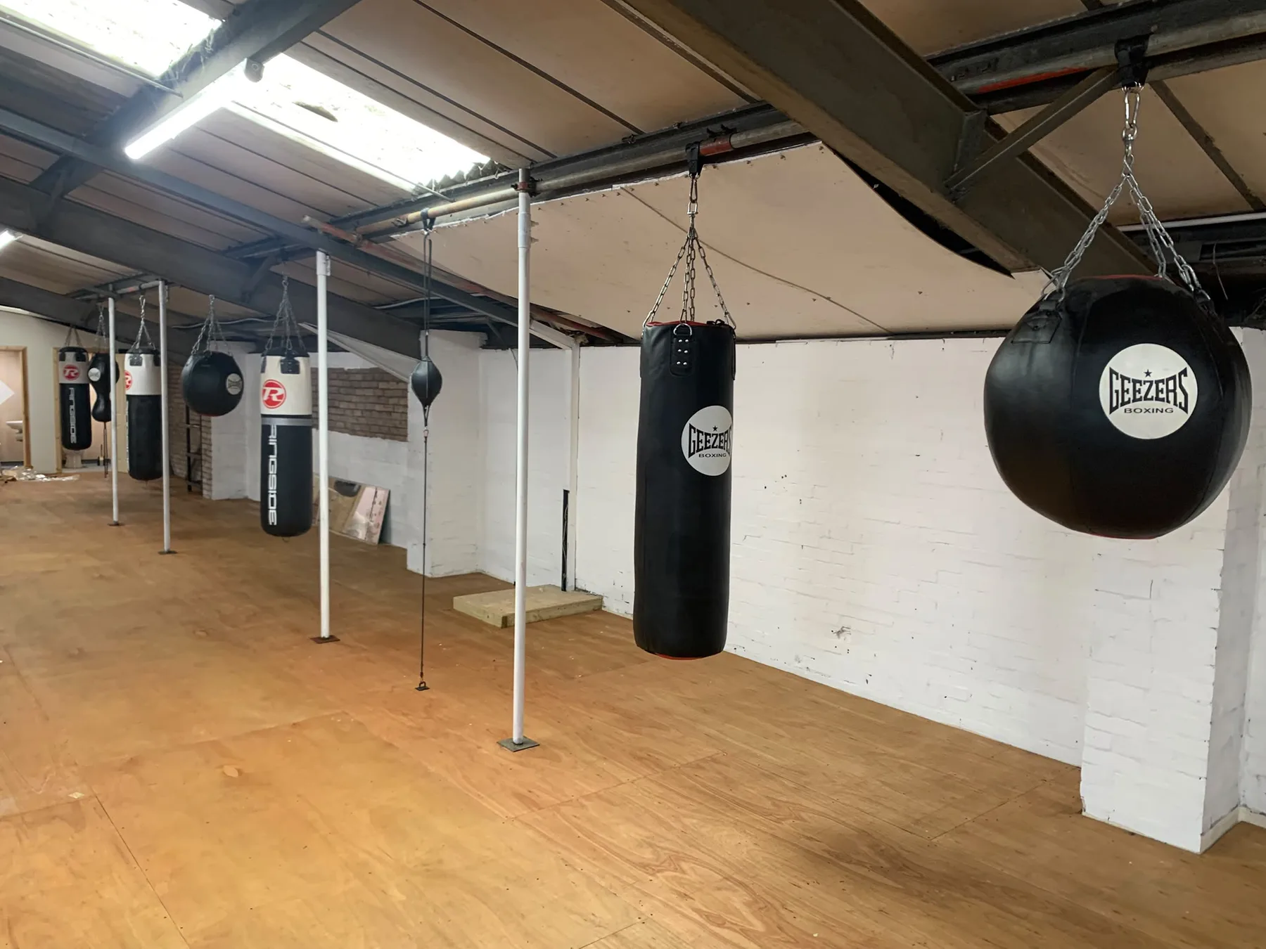 Row of heavy punch bags and a floor-to-ceiling ball on the bag floor